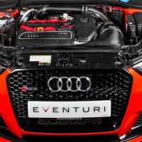 An open hood of an orange Audi RS3 reveals the engine and various components, situated in a dimly lit garage. The license plate reads "EVENTURI." The badge "quattro" appears below.