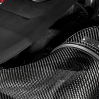 Engine intake system displaying a carbon fiber Eventuri air intake, with "TFSi" and "Eventuri" labels visible, amidst metallic engine components in a high-performance vehicle's engine bay.