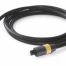 A black optical audio cable with gold connectors lies coiled on a white surface.