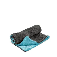 A partially rolled, two-tone microfiber towel with a dark grey exterior and light blue interior rests on a plain white surface, showcasing both colors prominently.