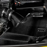 A carbon fiber engine air intake system labeled "EVENTURI" is installed in a vehicle's engine bay with surrounding metal, plastic parts, and blue fluid cap.
