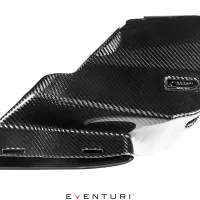 Carbon fiber engine cover with a glossy finish, featuring an embossed label "EVENTURI" and "MADE IN ENGLAND" and "Patented Design Delta". Set against a white background.