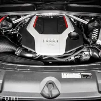 Car engine bay showing an Audi engine with a black and silver cover marked "TFSi," surrounded by various mechanical components, wires, and Eventuri carbon fiber intake. Text: "EVENTURI."