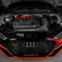A high-performance Audi engine, with an open hood, displays the TFSI engine labeled "quattro" in a dimly lit garage.