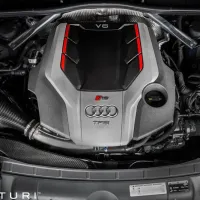 Audi V6 engine with red trim detailing, bearing logos for "Audi," "G S," and "TFSI." It is installed in a car engine bay, surrounded by various automotive components. Text: "EVENTURI."