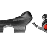 A carbon fiber engine cover and air intake with a red cone filter rest on a white background. The engine cover is contoured with a textured finish, while the air intake has a visible red filtration element.