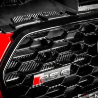 Grille with "RS6" badge on a red vehicle, focusing on the black hexagonal design, with "EVENTURI™" text in the corner. The background includes engine parts.
