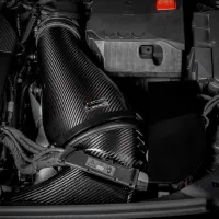 A carbon fiber air intake pipe, labeled "EVENTURI," is attached to an automobile's engine, surrounded by various engine components and wiring within the engine bay.