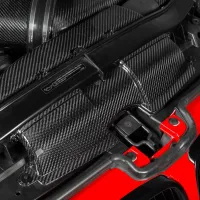 Carbon fiber engine covers resting on a vehicle's engine bay with a red car body front section visible. Text on the cover reads, "CASTROL RECOMMENDATION".