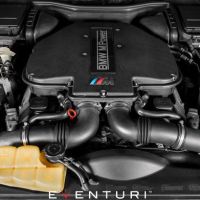 Engine bay of a BMW M Power vehicle with a V8 engine. Carbon fiber intake systems are visible on both sides, and the surroundings contain various engine components and fluids. Eventuri branding is at the bottom.