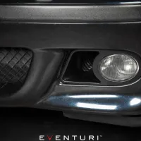 A close-up of a car's front bumper featuring a fog light on the left side next to a black mesh grill. Text: "EVENTURI" at the bottom.