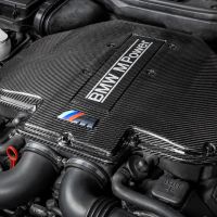 Carbon fiber engine cover labeled "BMW M Power" and featuring the BMW M logo, situated within an intricate car engine compartment.