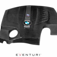 A carbon-fiber engine cover featuring a BMW logo and "Eventuri" branding. The cover includes a circular cutout and sculpted contours. The background is white with "EVENTURI" text below it.