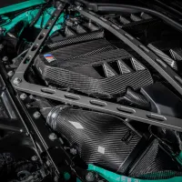 A car engine with carbon fiber parts and reinforced strut braces in a clean, well-lit engine bay showcasing performance-oriented modifications.