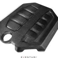 Carbon fiber engine cover with a sleek design featuring ridged patterns, positioned diagonally against a white background. Text at the bottom reads "EVENTURI".