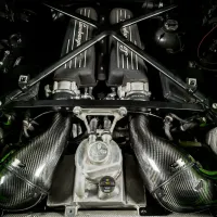Lamborghini-branded V12 engine block with twin air intakes and carbon-fiber components sits within a bright green engine bay, emphasizing the high-performance mechanics and sporty design of the vehicle.