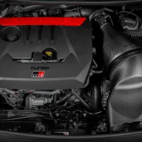 A black engine with a red accent labeled "turbo" and "GR" is mounted in a car's engine bay, surrounded by various mechanical components and wiring.