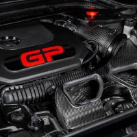 A high-performance car engine labeled "GP" with black and carbon fiber components in a well-organized engine bay.