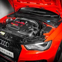 A bright orange Audi car with an open hood revealing the engine. The front grille features an "EVENTURI" license plate. The vehicle is positioned in a garage with gray concrete walls.