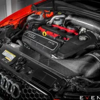 Car engine with a prominently branded logo and red-highlighted parts, surrounded by glossy carbon fiber components in a well-lit garage. Text: "EVENTURI" and "TFSi."