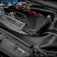 A carbon fiber-covered car engine with "TFSi" and Audi rings is mounted in a blue vehicle's engine compartment. The Venturi air intake system is prominent with sleek black tubing.