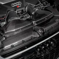 An Audi R8 engine with “Eventuri” intake components in a carbon fiber finish, situated in the engine bay of the car, showcasing the manufacturer's logo prominently.