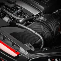 Carbon fiber air intake system affixed to a car engine bay with surrounding components and hoses; "EVENTURI™" text displayed in the bottom right corner.