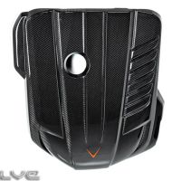 Black carbon fiber engine cover with a central circular opening and an orange V-shaped emblem, featuring ridged textures. "EVOLVE" text appears in the bottom-left corner.