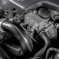 A carbon fiber air intake system is installed in a car engine bay surrounded by various engine components. The image text reads "EVENTURI™".
