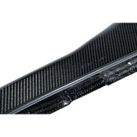A black carbon fiber material with a textured, woven pattern appears close-up, displaying minor scratches. It is set against a plain white background.