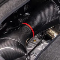 A black carbon fiber intake pipe with red lettering "EVENTURI" sits within an engine bay, surrounded by dark, fabric-lined components and metallic elements.