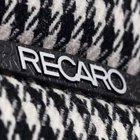 The "RECARO" logo is displayed on a black and white houndstooth-patterned fabric, suggesting a close-up view of a seat or upholstery.