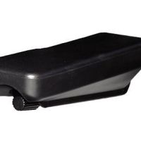 A black plastic rectangular case with a small wheel, resting on a white surface, possibly a guitar capo or clip.