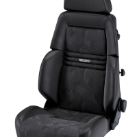 The image shows a black car seat with "RECARO" embroidered on the backrest, featuring ergonomic padding and adjustable side knobs, isolated against a plain background.