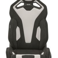 Black and white high-back racing car seat labeled "RECARO," positioned in an all-white background setting. The seat features distinct cushioning and cutout designs for enhanced support and aesthetics.