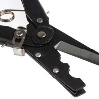 A pair of black, metal crimping pliers with cutting blades, partially open, lying on a white surface. A coiled spring is visible near the handles, indicating its functionality.