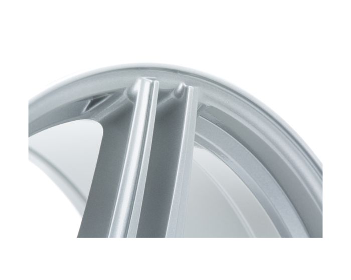 A close-up of a silver metallic car wheel rim, showing intricate grooves and a smooth, curved surface, against a white background.