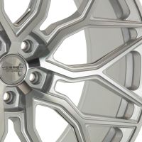 A silver alloy wheel with intricate, angular spokes; the center cap displays the text "VOSSEN HYBRID FORGED." The wheel is shown in close-up, showcasing its modern design.