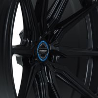 A black Vossen car rim with a multi-spoke design, showcasing the brand logo and model information (“VOSSEN HYBRID FORGED”) in a blue circle, placed on a white background.