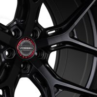 Black alloy wheel features intricate spoke design with a red and silver center cap. Text reads: "VOSSEN, HYBRID FORGED, ENGINEERED FOR PERFORMANCE, EST. 2006, DESIGNED IN MIAMI, FLOW FORMED WHEEL."