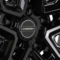 High-gloss black wheel center cap with a circular emblem displaying "VOSSEN" in a stylized font, surrounded by glossy, intricately designed spokes.