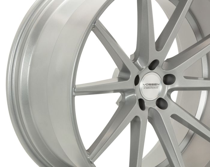 A metallic silver alloy wheel with ten spokes radiates from the center hub. The center cap features the text "VOSSEN HYBRID FORGED." The background is plain white.