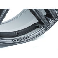 A metallic wheel rim with stylized grooves features the embossed text “VOSSEN” along its edge, set against a white background.