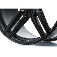 A glossy black car wheel rim with a modern, angular design rests against a plain white background. The word "VOSSEN" is etched into the rim's edge.