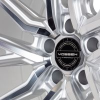 A polished silver alloy wheel showcases its intricate design in a well-lit studio. Center cap displays: "VOSSEN HYBRID FORGED, VOSSEN WHEELS, ESTD. 2006 USA, PASSION - PERFORMANCE - PRECISION."