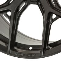 A metallic car wheel rim with intricate spokes sits in a plain background. The brand "VOSSEN" is embossed along the edge near a bolt hole.