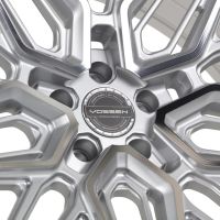A silver alloy wheel features a complex geometric design; the center cap reads: "Vossen Hybrid Forged, Vossen Wheels, Est 2006, USA, Passion - Performance - Precision." It’s set against a white background.