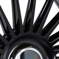 Black metal wheel spokes radiate symmetrically from a shiny central hub, reflecting light in a sleek, industrial setting. No text is present.