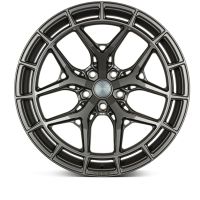 A dark metallic wheel rim features intricate geometric spoke patterns against a plain background. Text on the center cap reads: "Wheelexclusive."