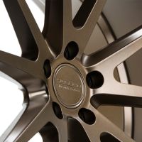 A bronze, multi-spoke wheel rim featuring the embossed text "VOSSEN FORGED HC-3" in a studio setting with soft lighting highlighting its metallic finish.